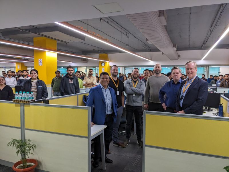 RxLogix colleagues gathered among yellow office partitions at the company's Noida town hall