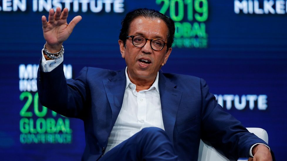 Rajeev Misra gesturing while seated onstage at the 2019 Milken Institute Global Conference