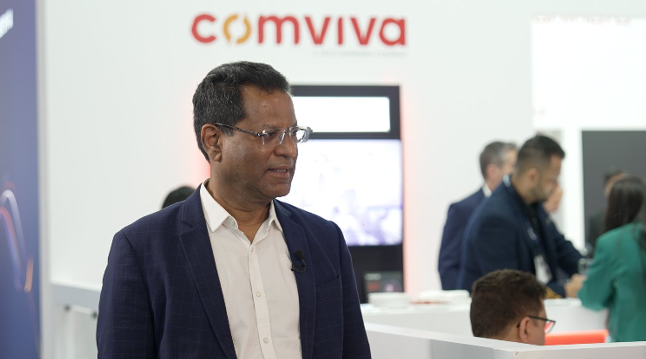 Rajesh Chandiramani speaking during a filmed interview at a Comviva exhibition booth