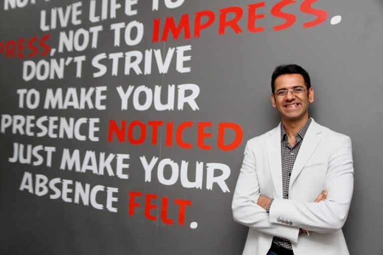 Rajiv Lamba smiling beside a wall of large motivational lettering