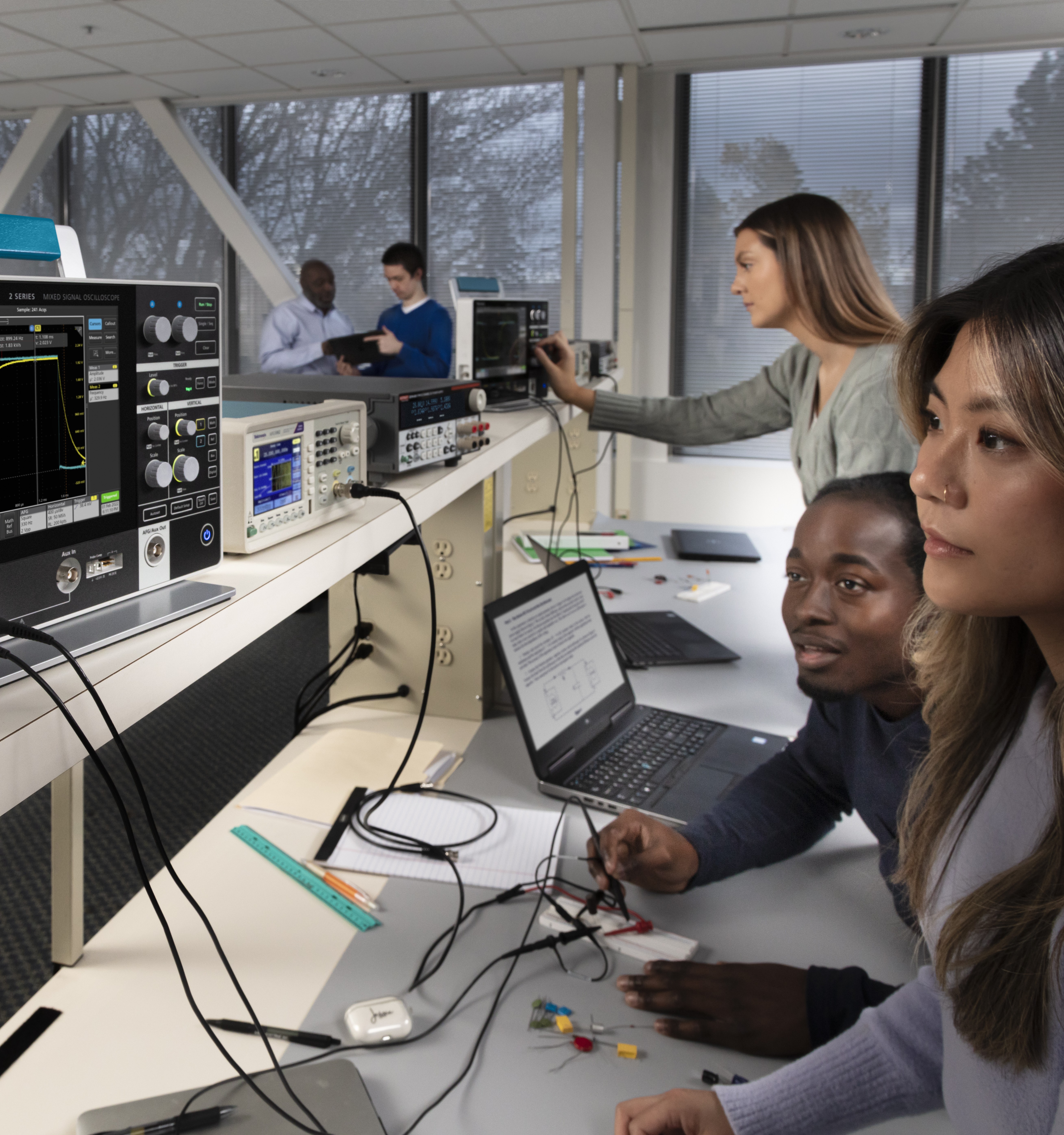 A group learning with Tektronix oscilloscopes at an electronics workbench