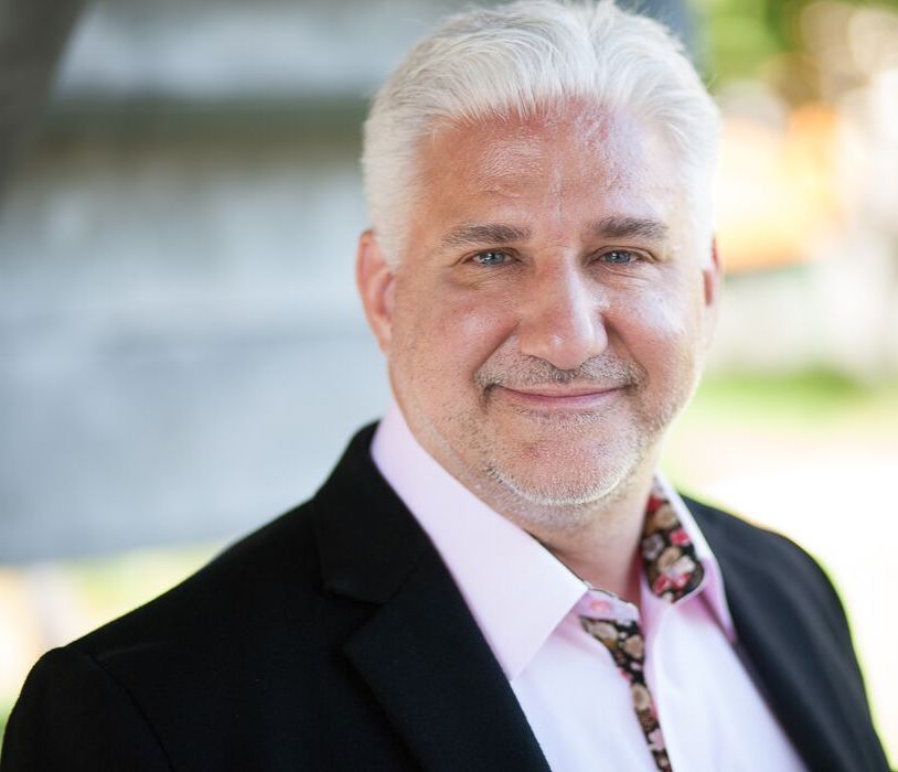 Ralph Dandrea in a dark jacket and patterned shirt, in the press photograph accompanying his 2019 Rochester interview