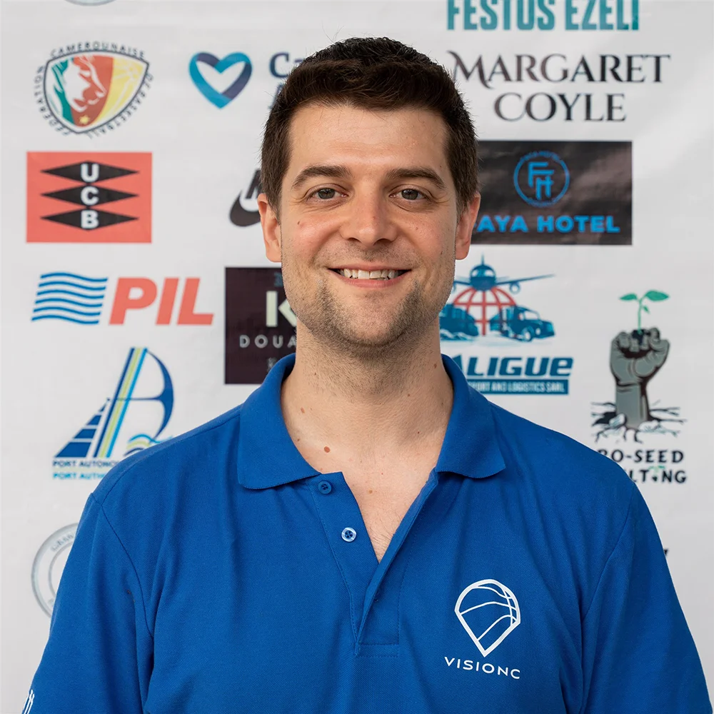 Ralph Passarella wearing a blue VisionC shirt in front of an event sponsor backdrop