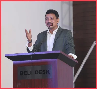 Ramesh Vayyavuru speaking into a microphone behind a lectern at Soft Suave’s anniversary