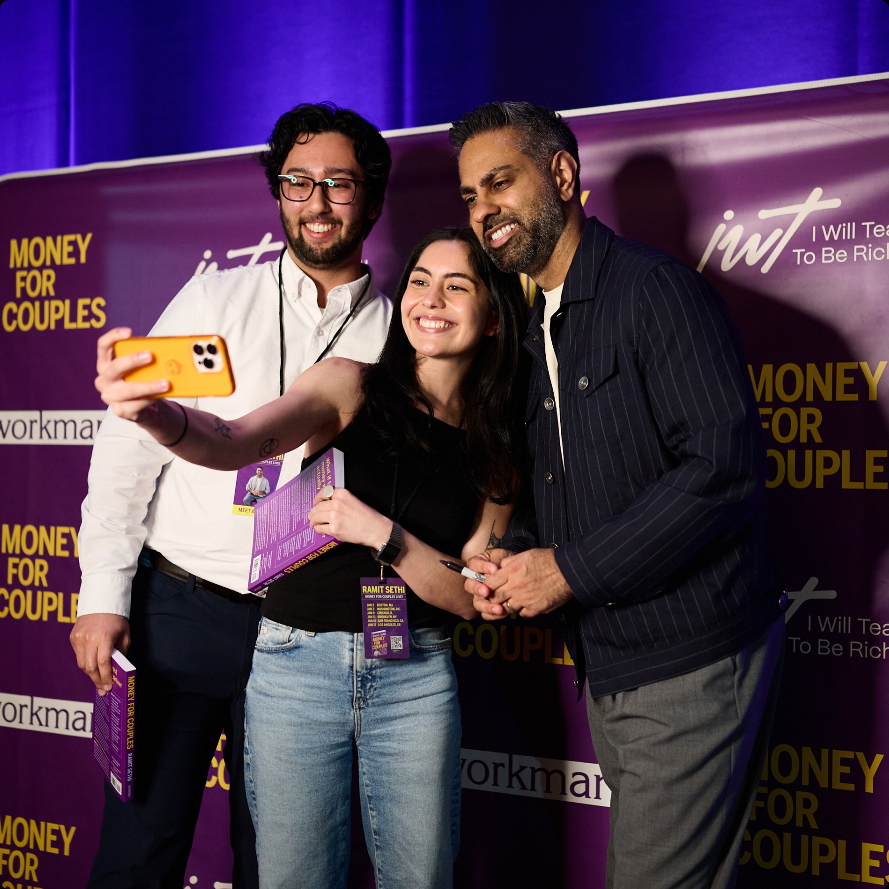 Ramit Sethi posing with guests in front of a Money for Couples backdrop