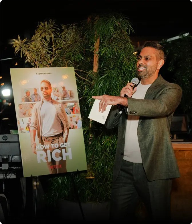 Ramit Sethi speaking onstage beside a Rich Life display