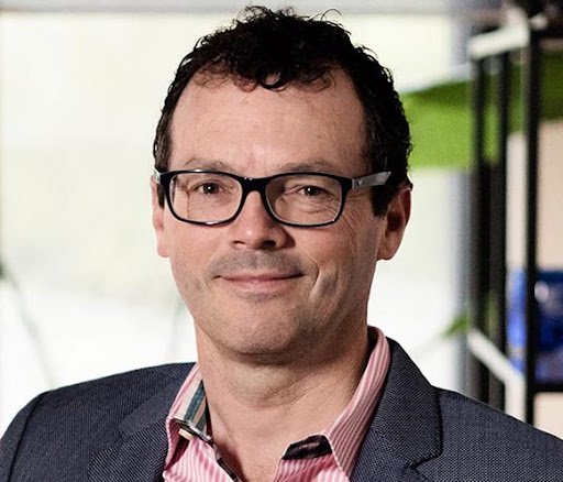 Randall Julian wearing glasses and a dark jacket in a photograph accompanying his 2022 interview