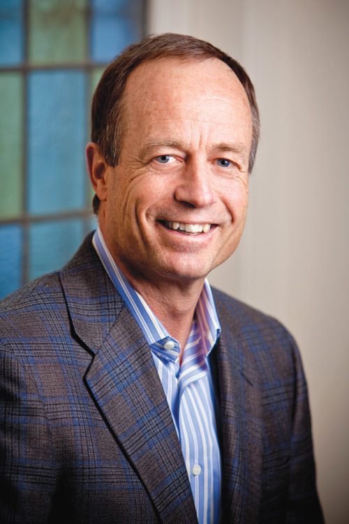 Randall Talbot in a checked jacket and striped shirt, in an archival Symetra-era portrait