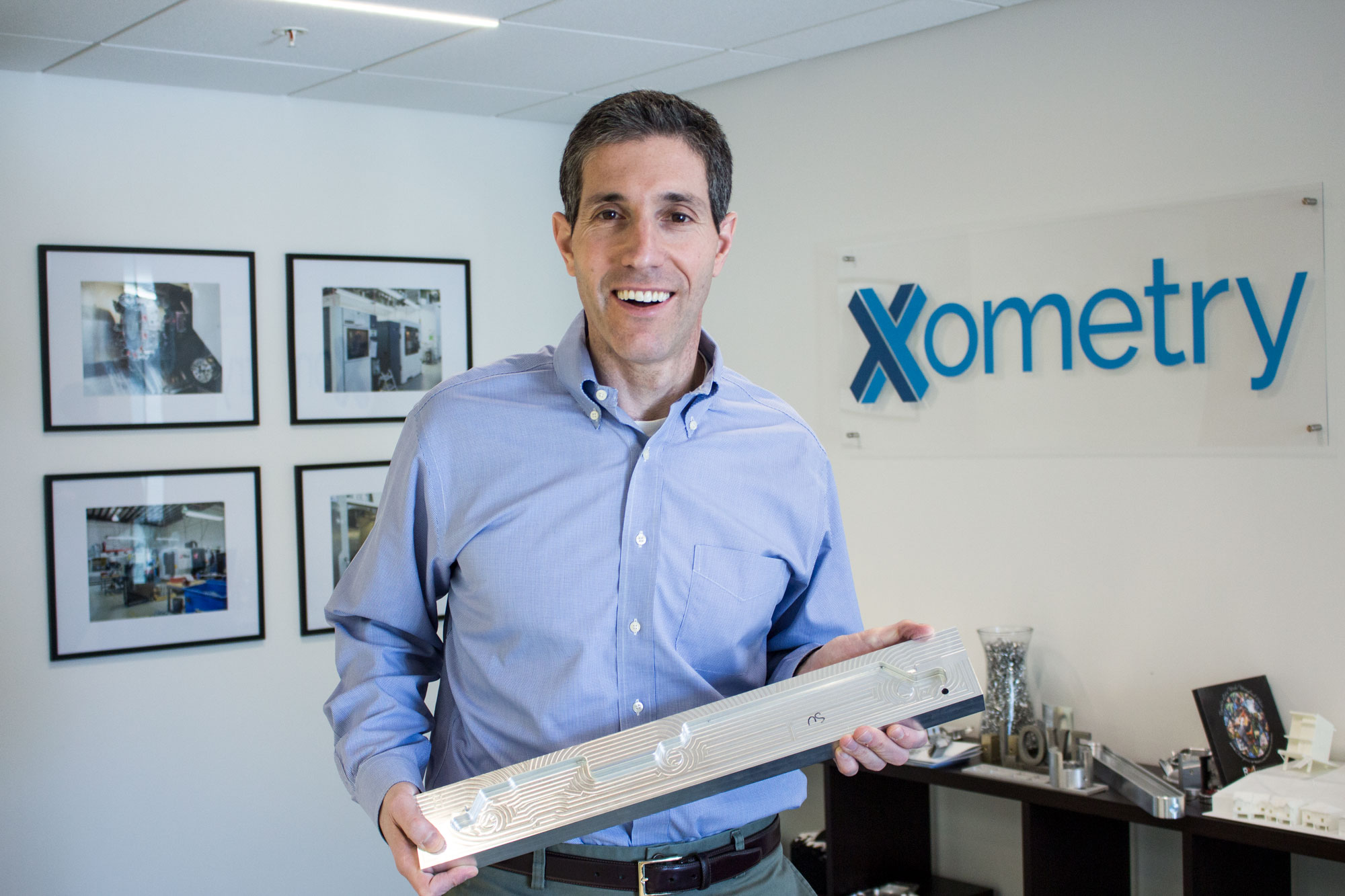 Randy Altschuler at Xometry holding a long machined metal component