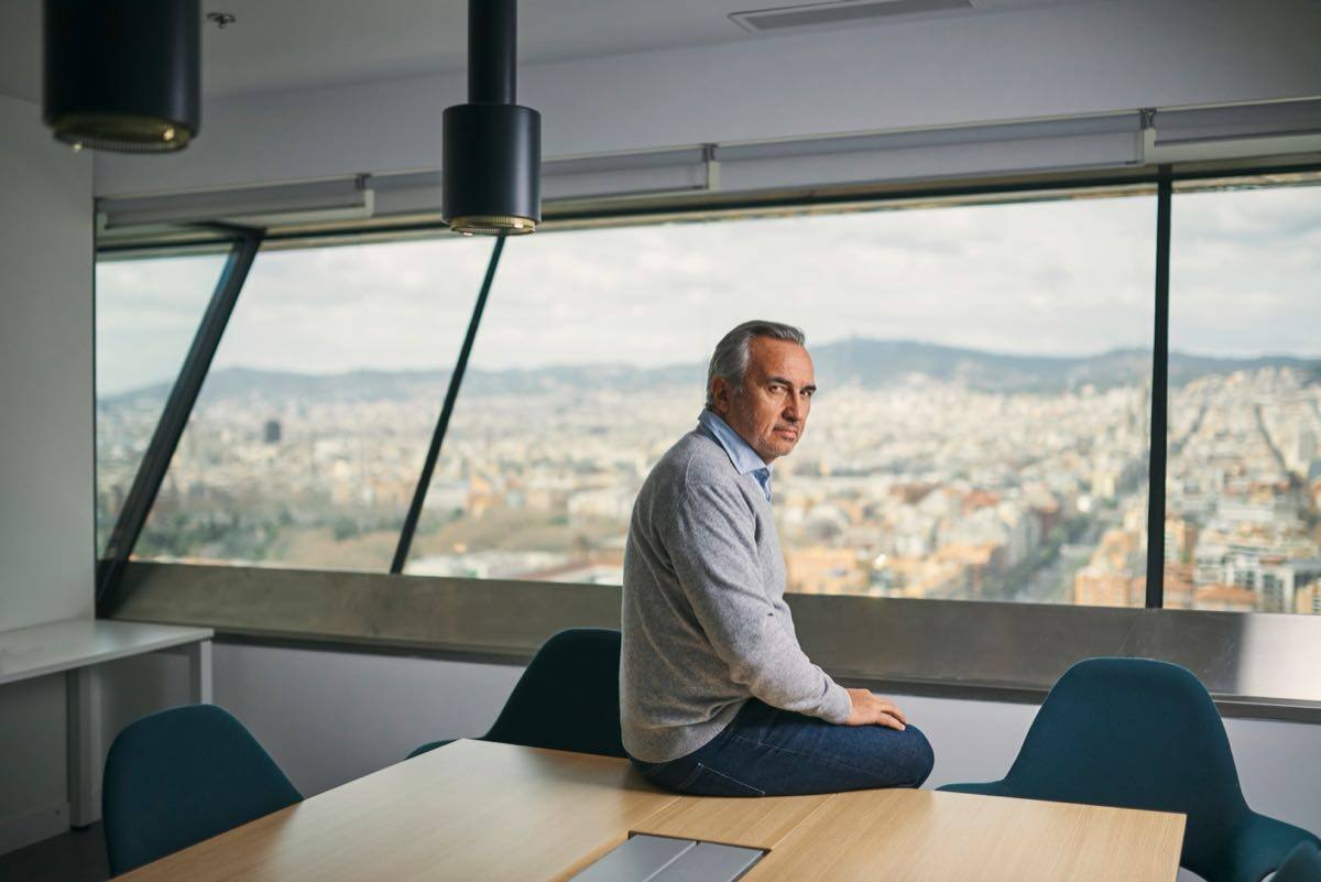 Raphael Dana sitting on a table in a meeting room overlooking a city