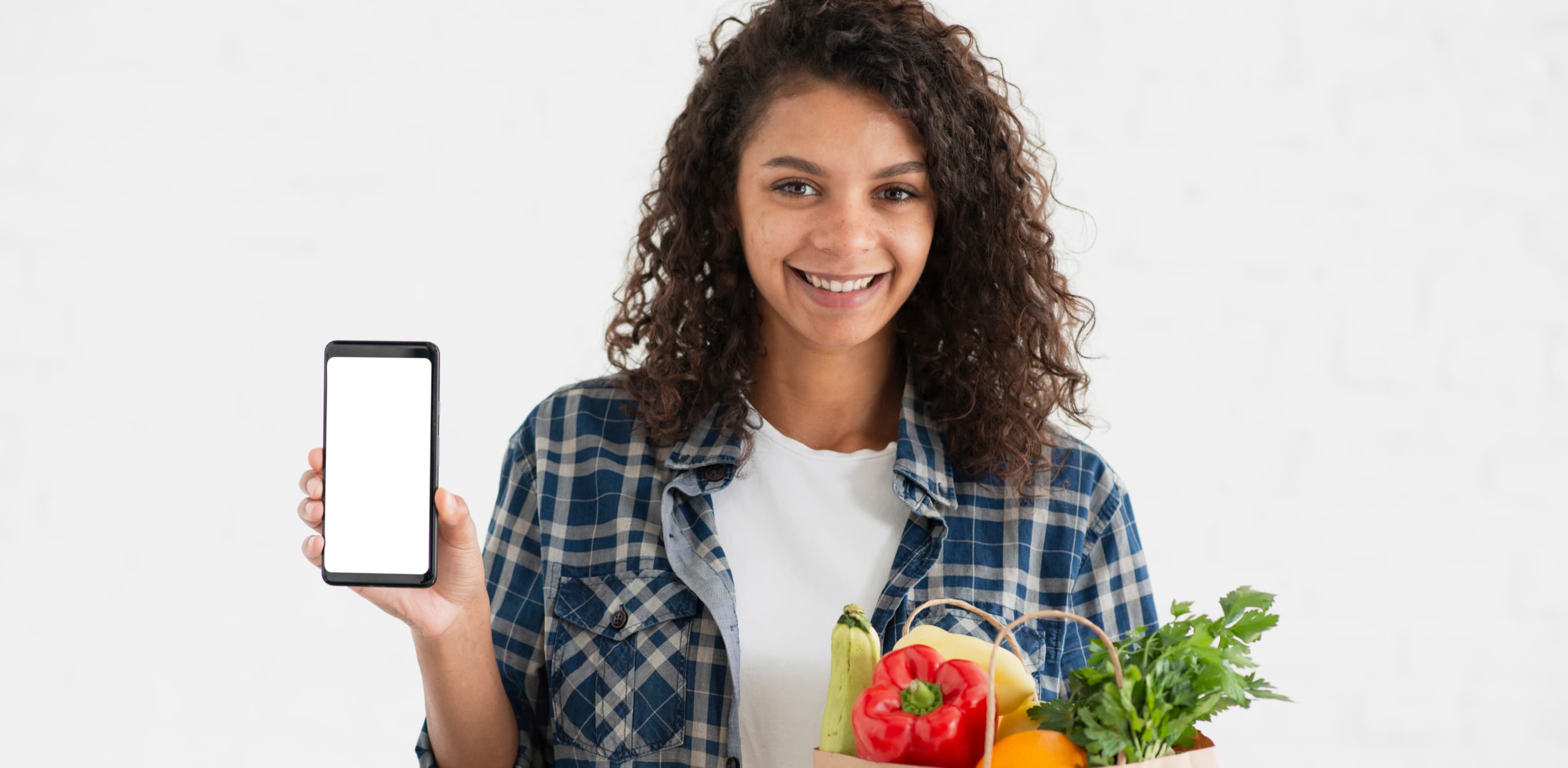 Illustrative grocery shopper holding a phone beside a bag of vegetables