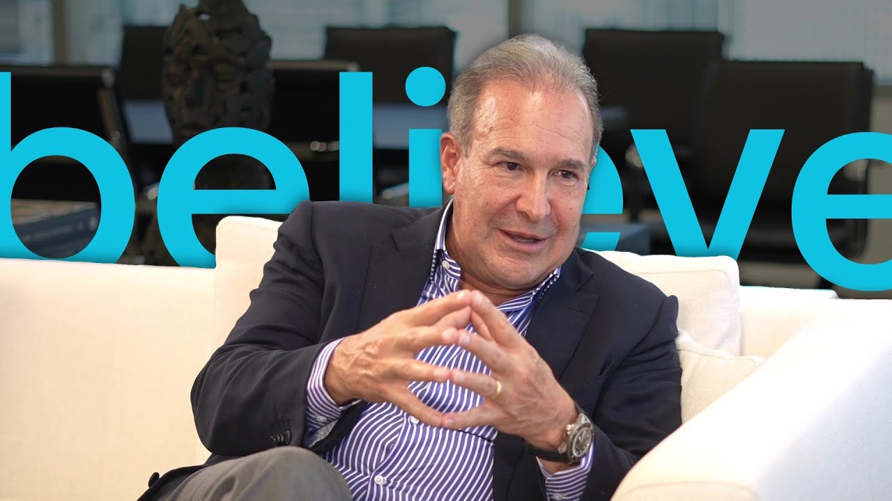 Raul Henriquez seated on a white sofa during his Funds Society video interview