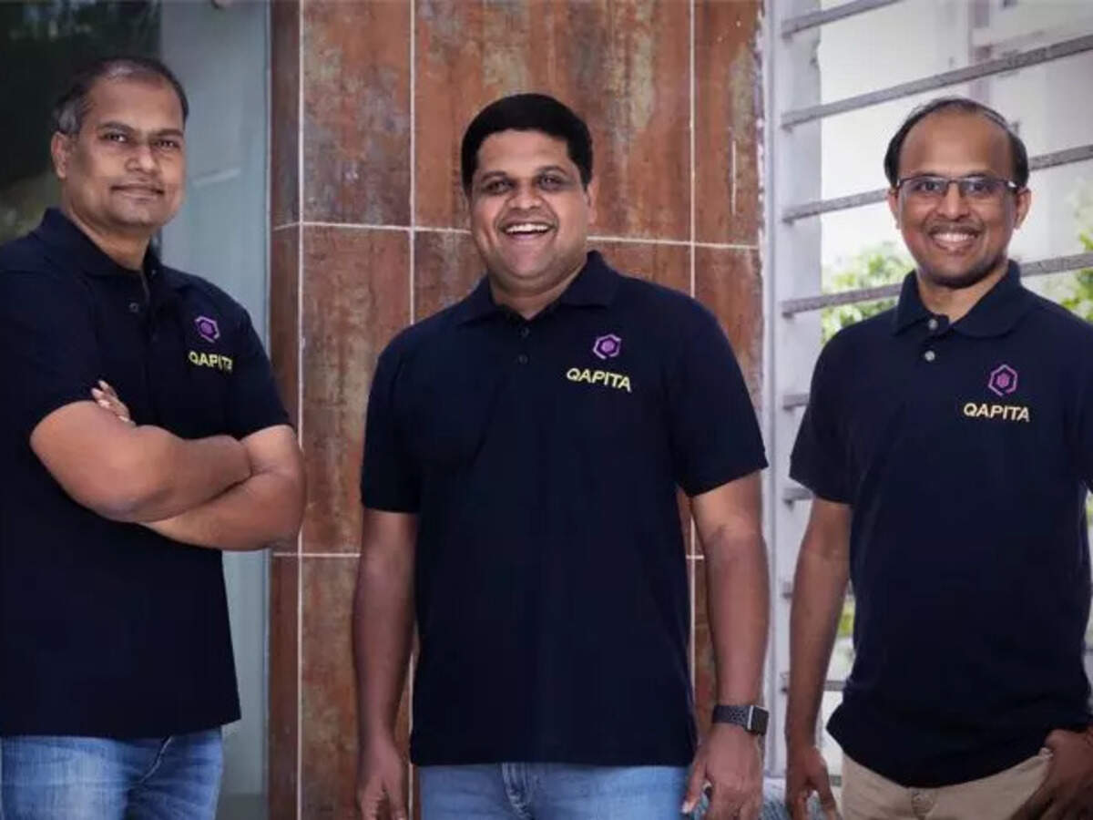 Qapita's three cofounders together in matching navy Qapita polo shirts; Ravi stands in the center
