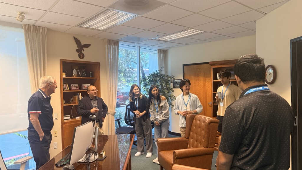 Ray Melissa at left, talking with students gathered in his office during a May 2026 headquarters visit