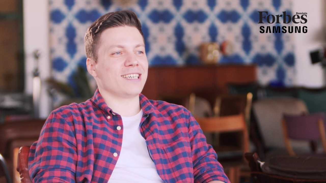 Razvan Creanga speaking during a Forbes Romania interview, wearing a red and blue checked shirt