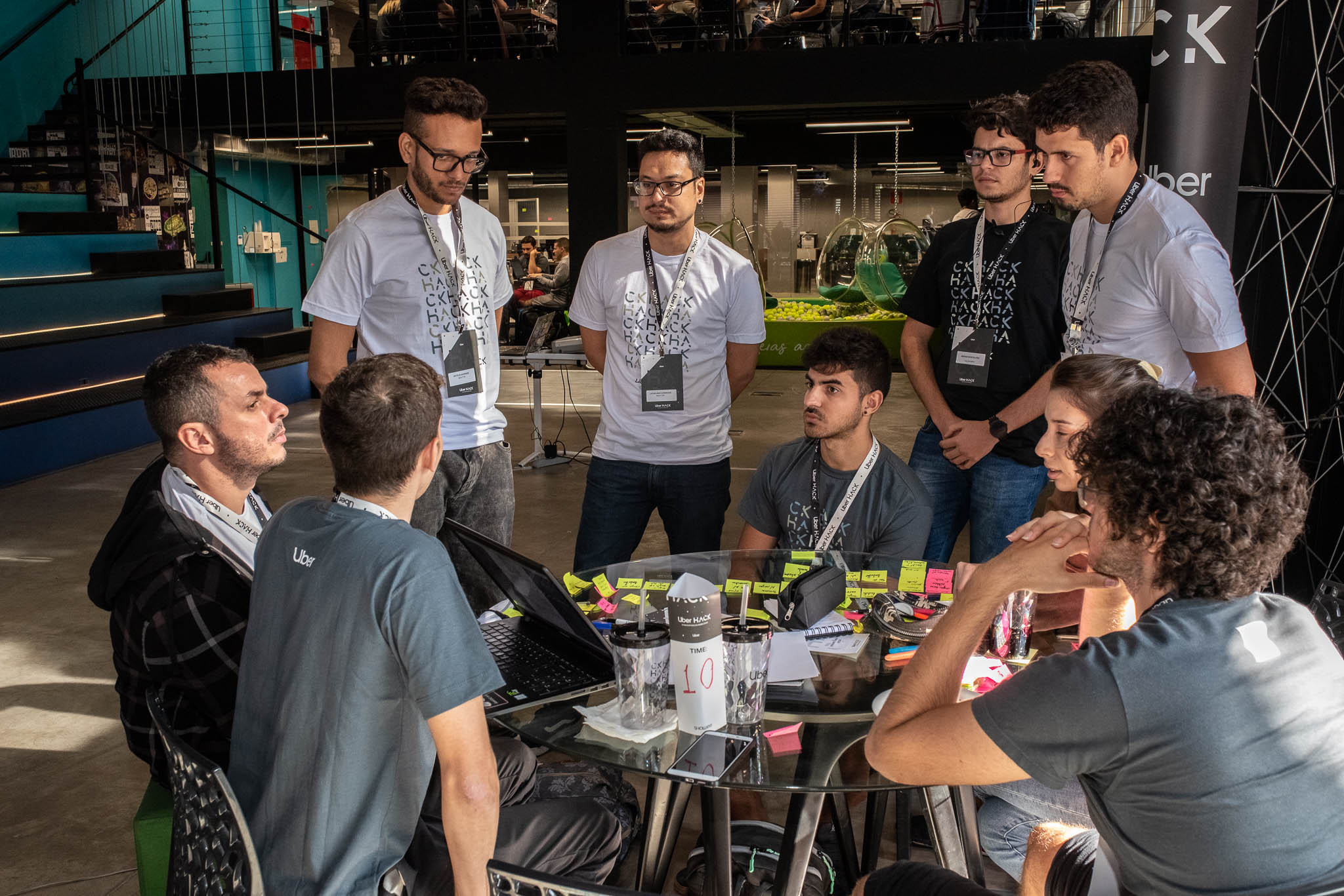 Uber Hack participants gathered around a table with a laptop and sticky notes at Órbi