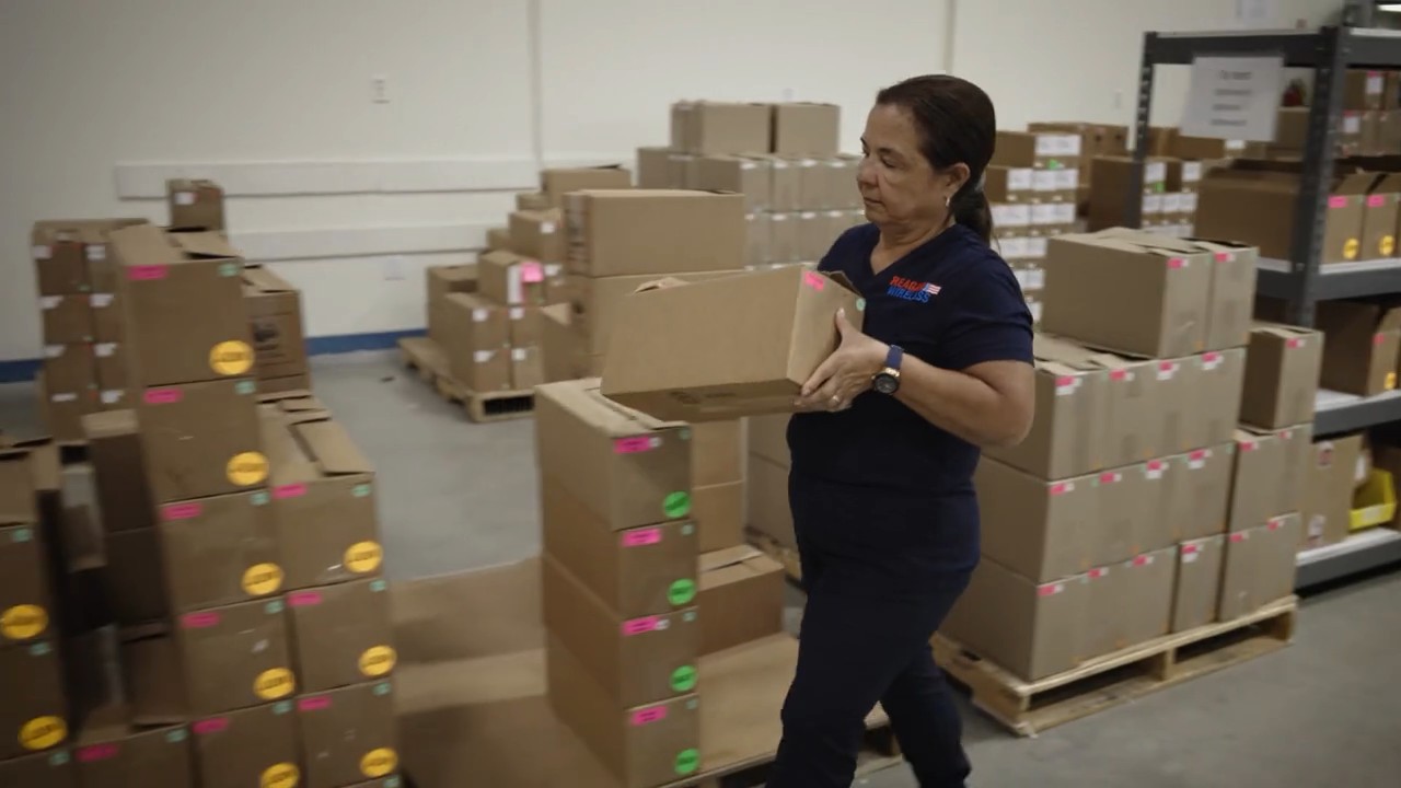 A Reagan Wireless employee moving boxed inventory across the warehouse floor