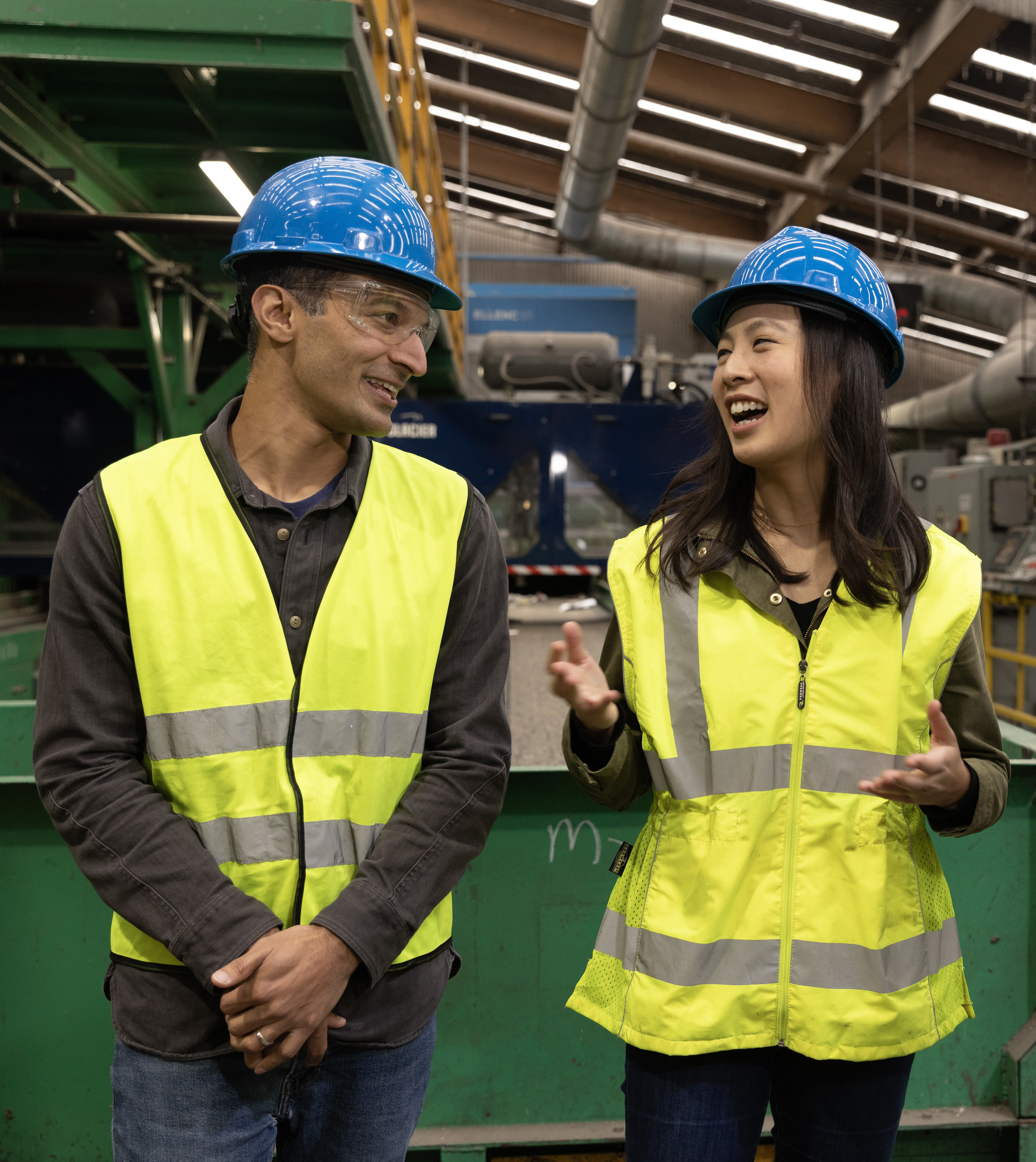 Glacier co-founders Areeb Malik and Rebecca Hu-Thrams wearing blue hard hats and high-visibility vests at a recycling facility