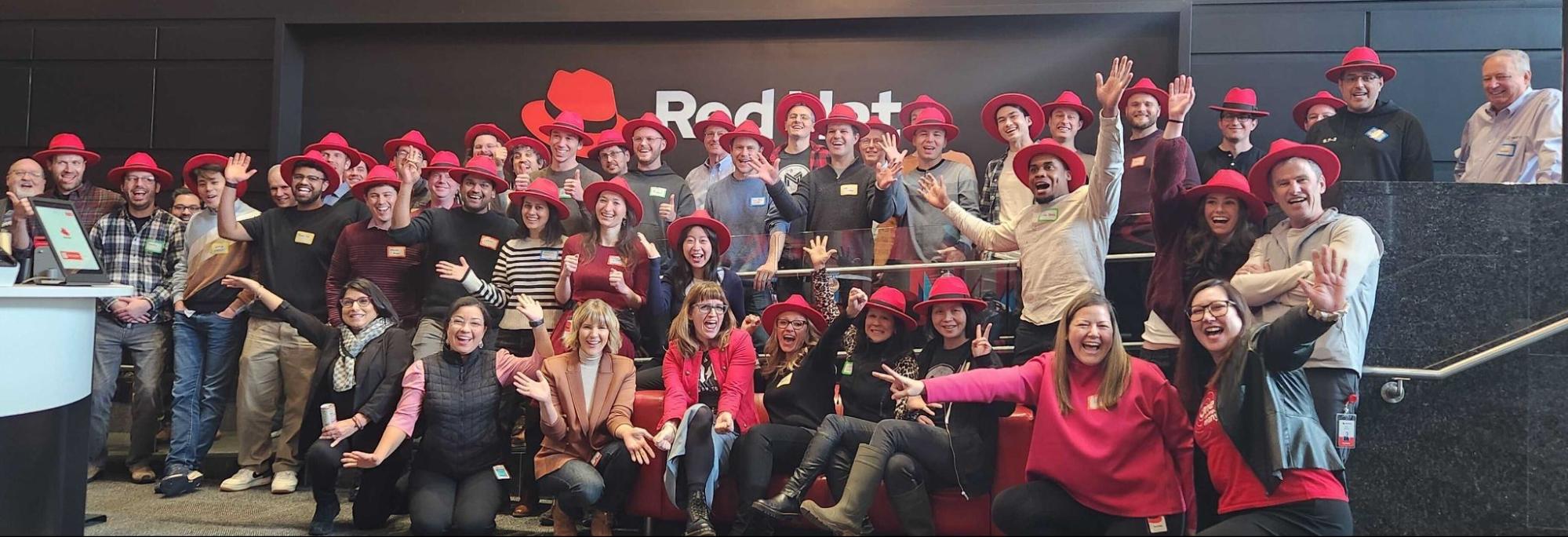 A large group of Red Hat employees wearing red hats in a company lobby
