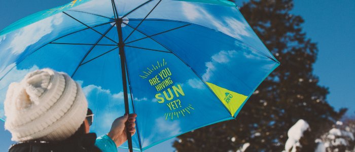 A Visit Idaho umbrella opened to reveal blue sky and a yellow sun graphic