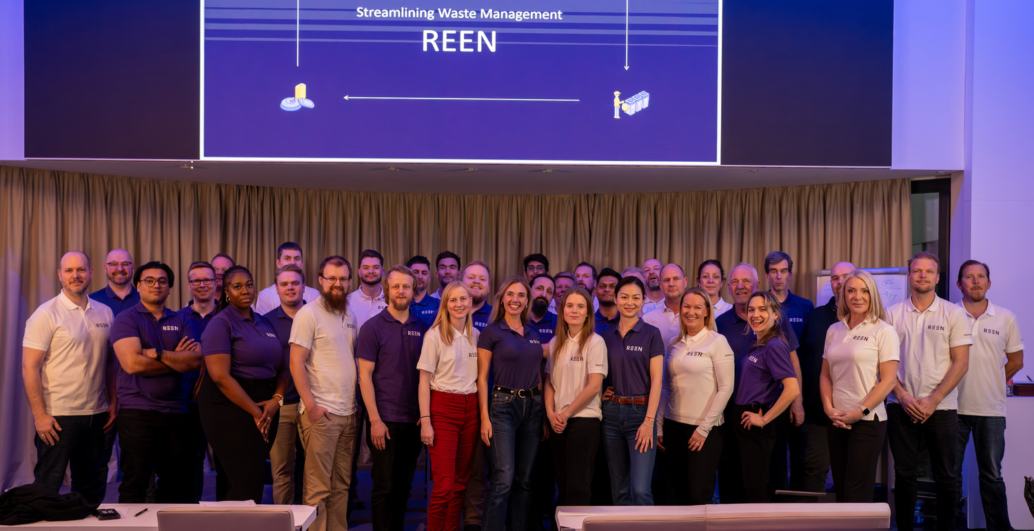 REEN team gathered in front of a presentation screen