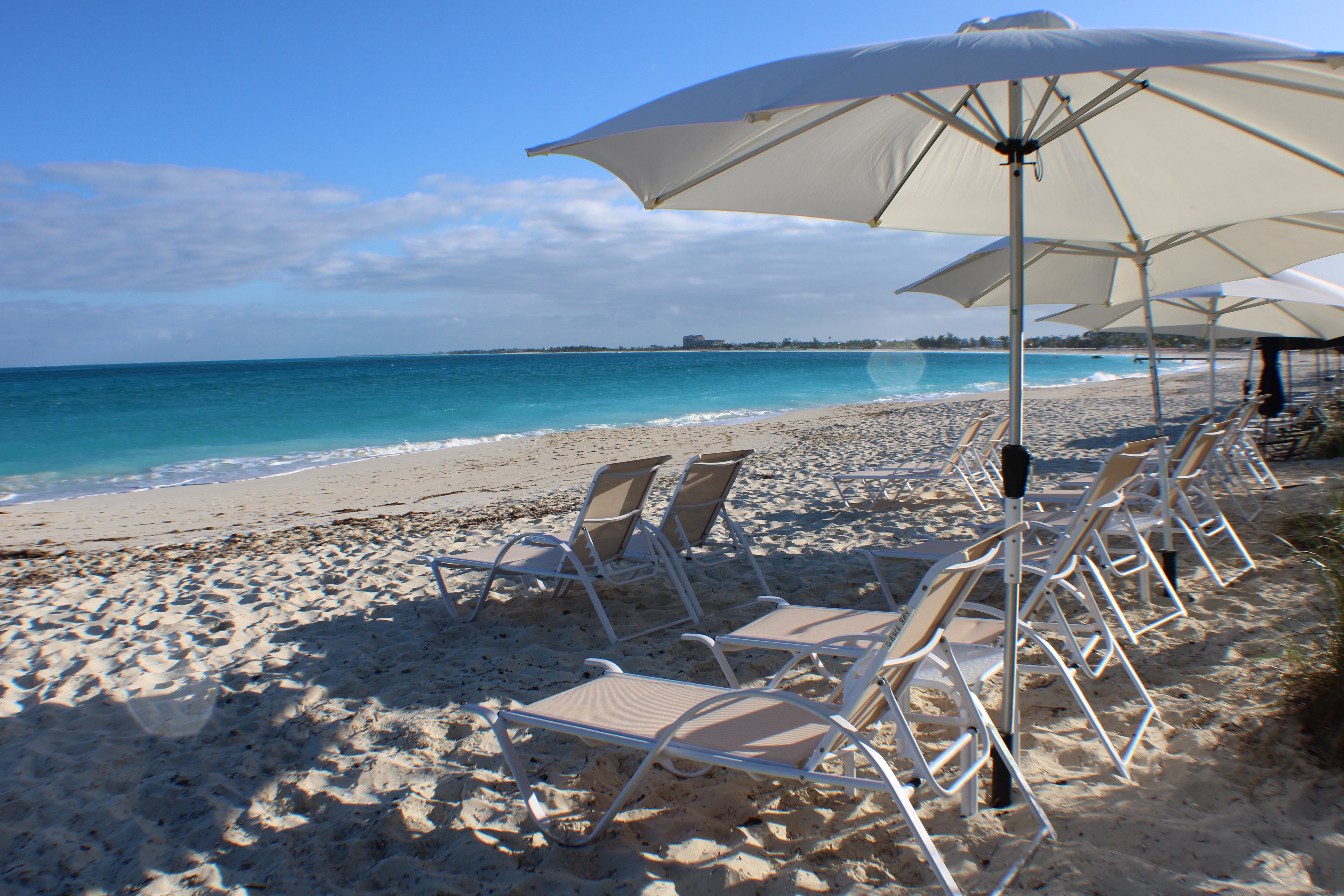 White umbrellas and beach chairs beside turquoise water at Grace Bay