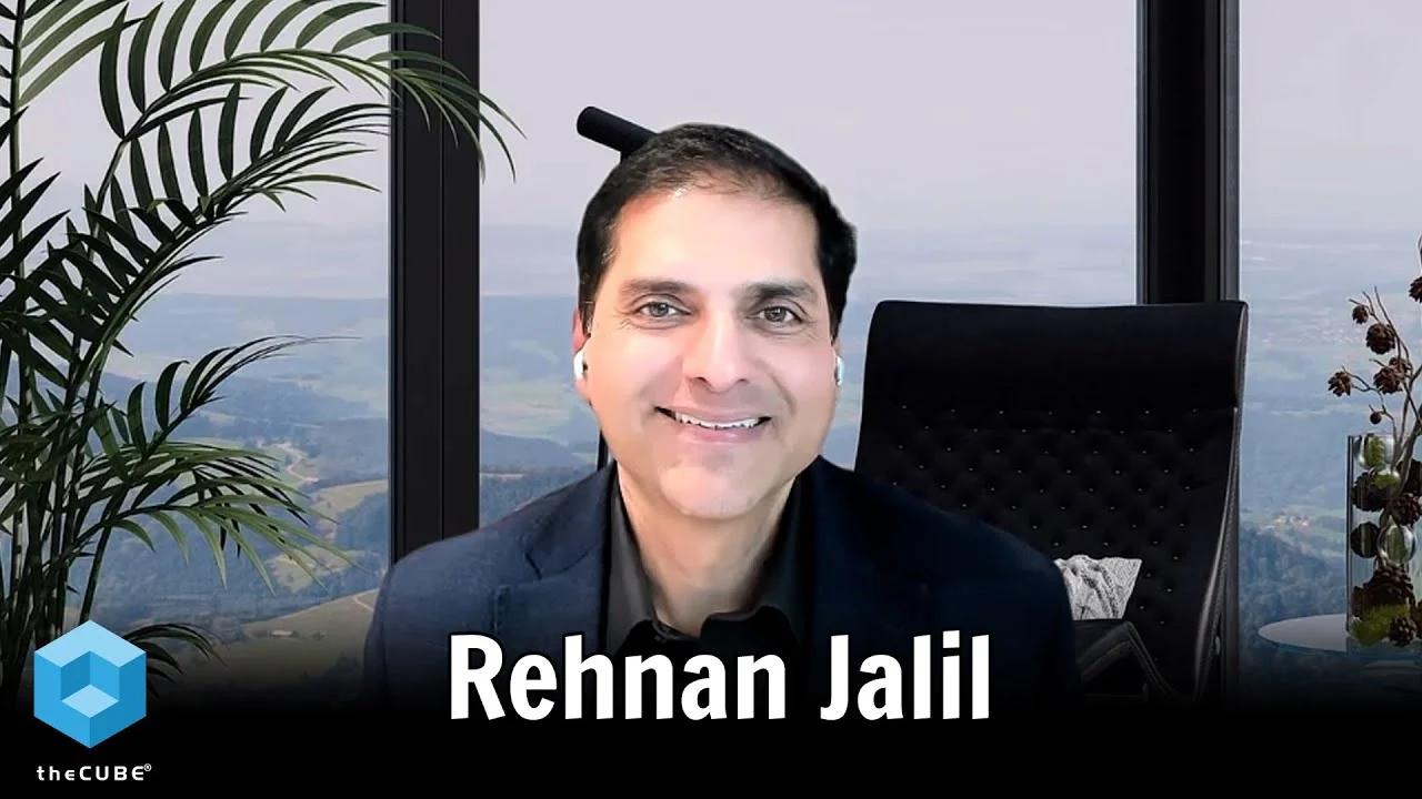 Rehan Jalil speaking remotely in a theCUBE interview, seated beside a window and plants.