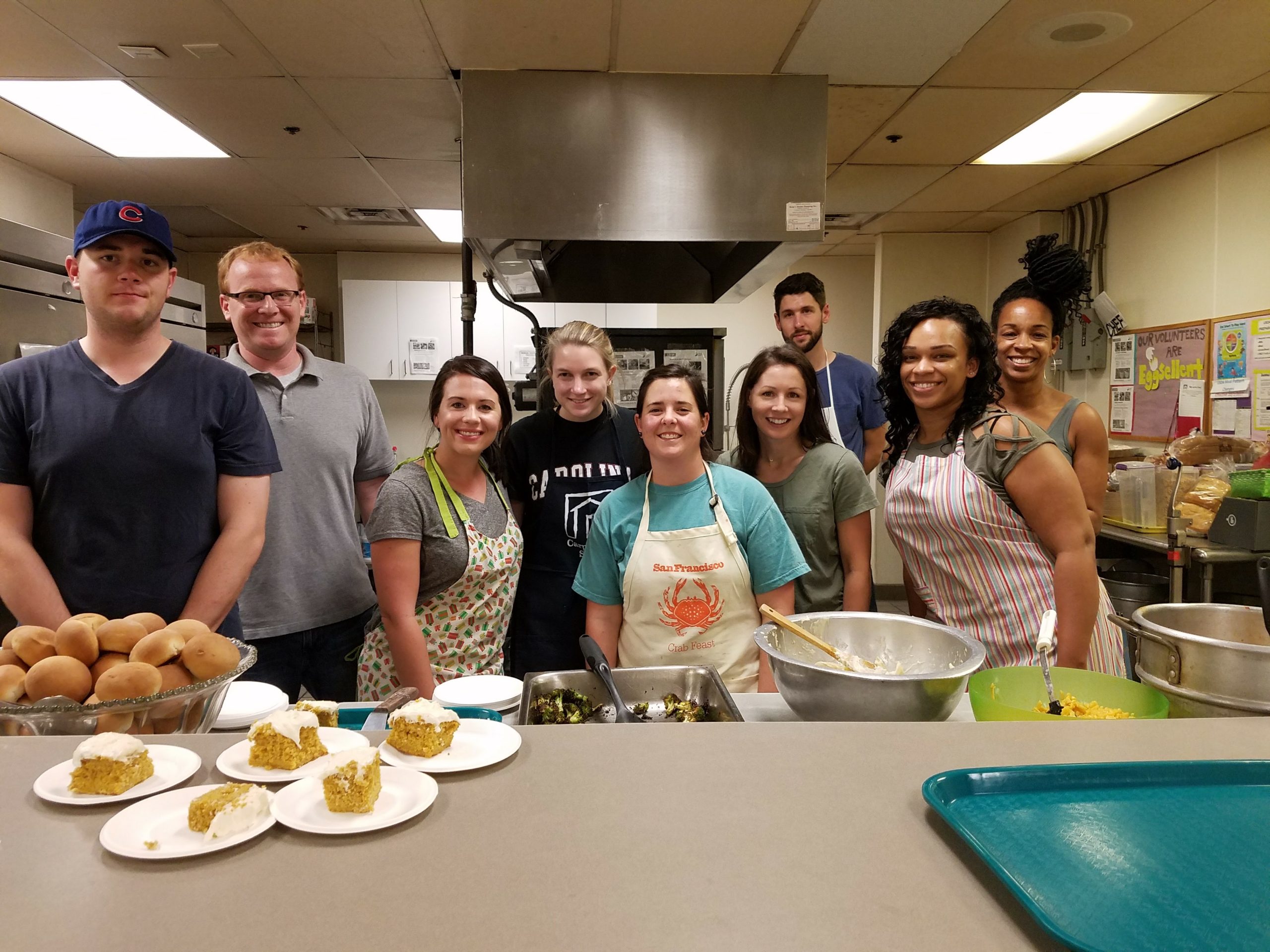 Reingold volunteers in aprons serving food together in a community kitchen