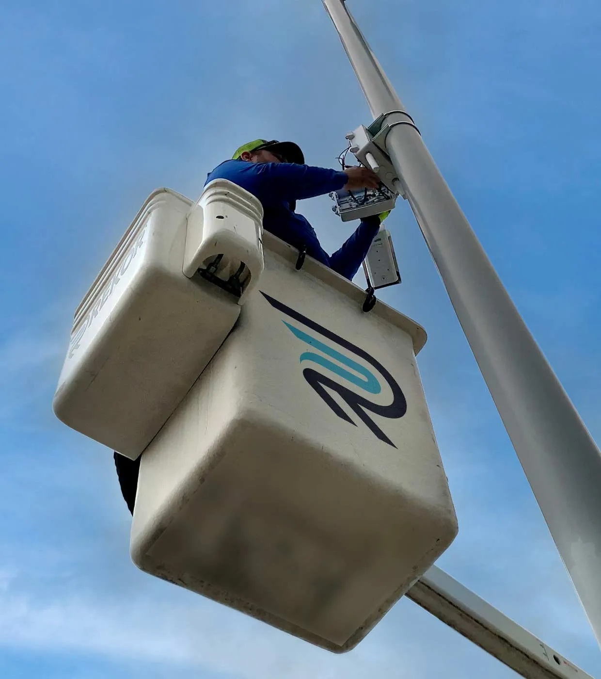 A technician in a bucket truck installs a roadside camera on a pole