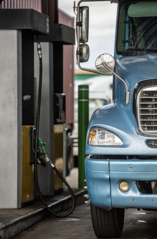A blue freight truck beside diesel fuel pumps