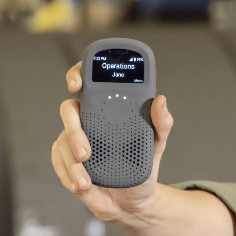 A hand holding the rugged RelayX smart radio with its operations channel displayed