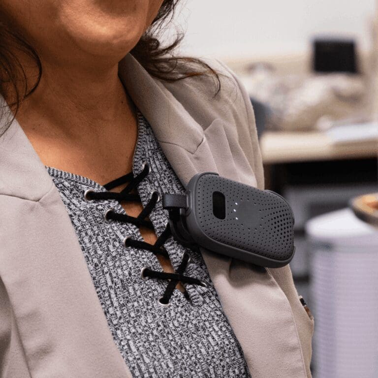 A frontline worker wearing a compact RelayM device clipped to a jacket