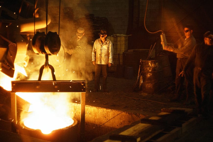 Reliance Foundry workers gathered around a ladle of molten metal