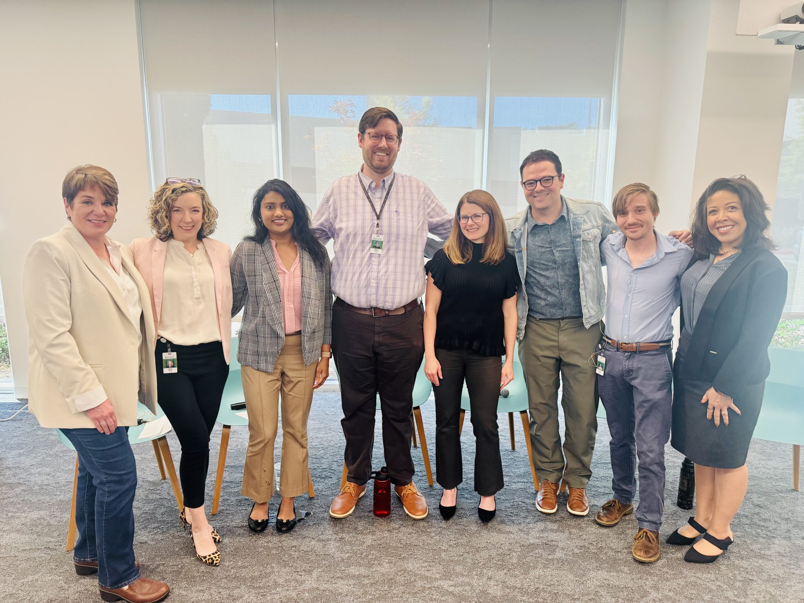 A group of Relias employees standing together in a bright office