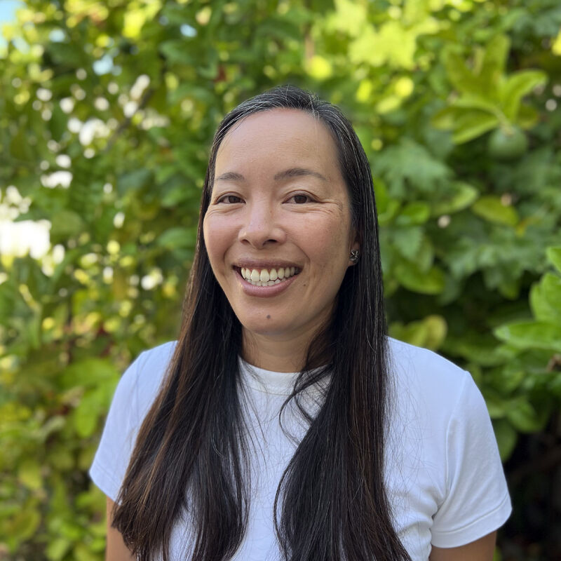 Renee Hall smiling outdoors against green foliage