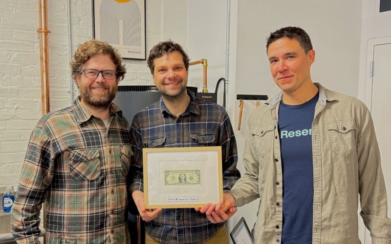 Three Reserve colleagues holding a framed First Reserve Dollar