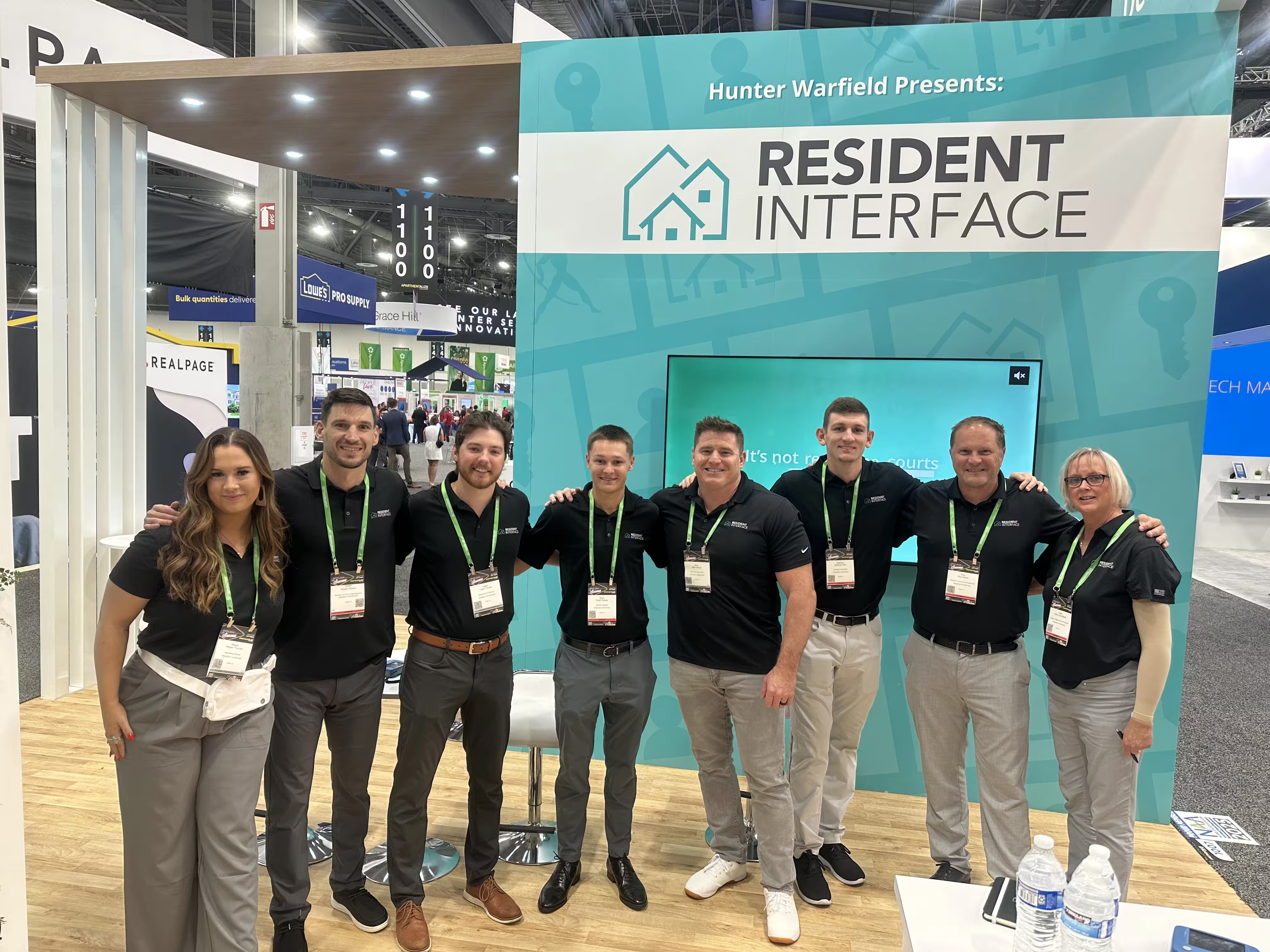 Eight Resident Interface team members standing at the company’s Apartmentalize exhibition booth