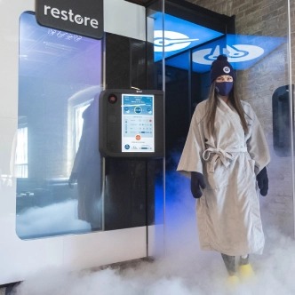 A customer using a whole-body cryotherapy chamber at Restore Hyper Wellness