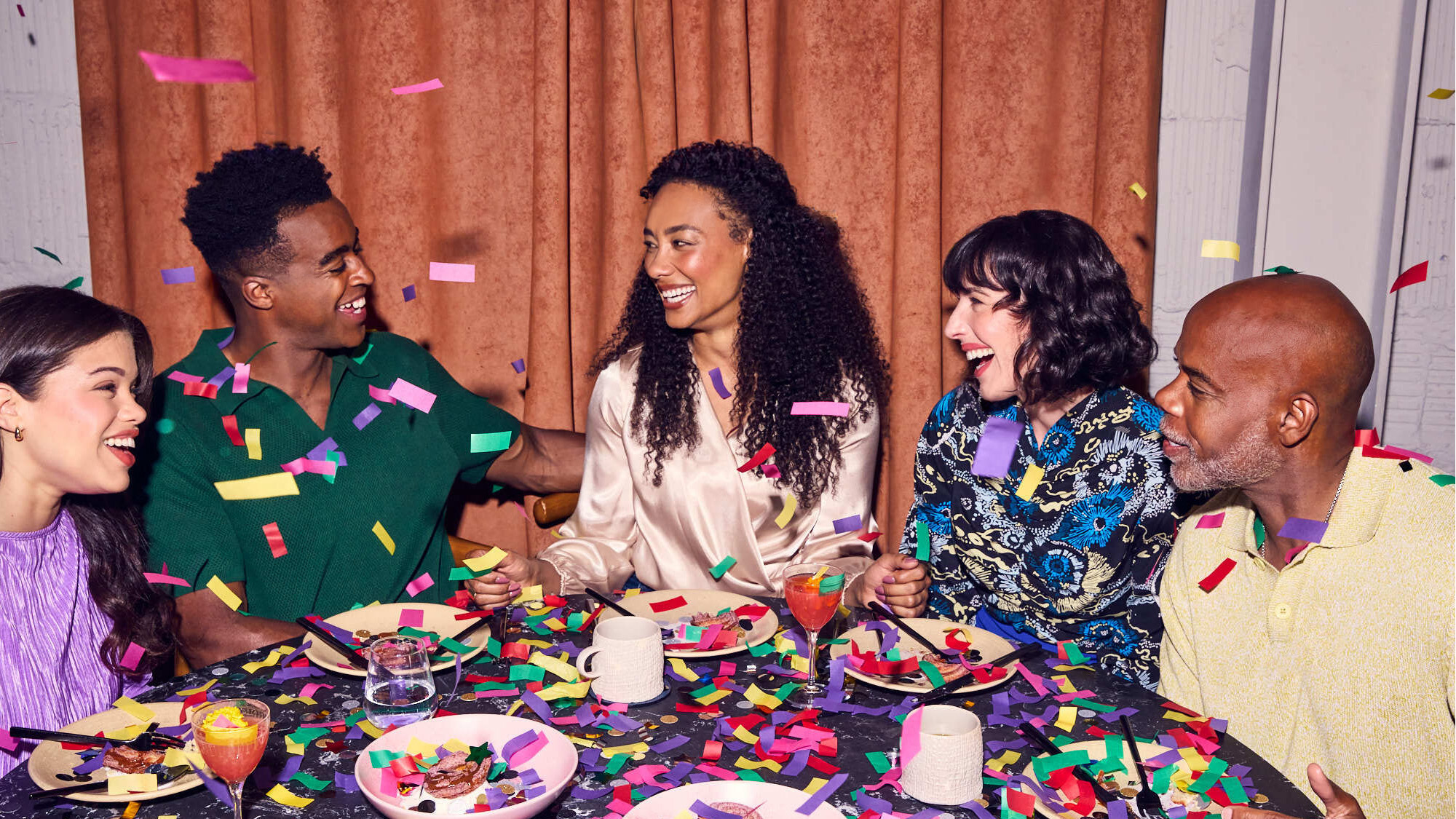 Friends celebrating around a restaurant table in a Resy tenth-anniversary campaign image