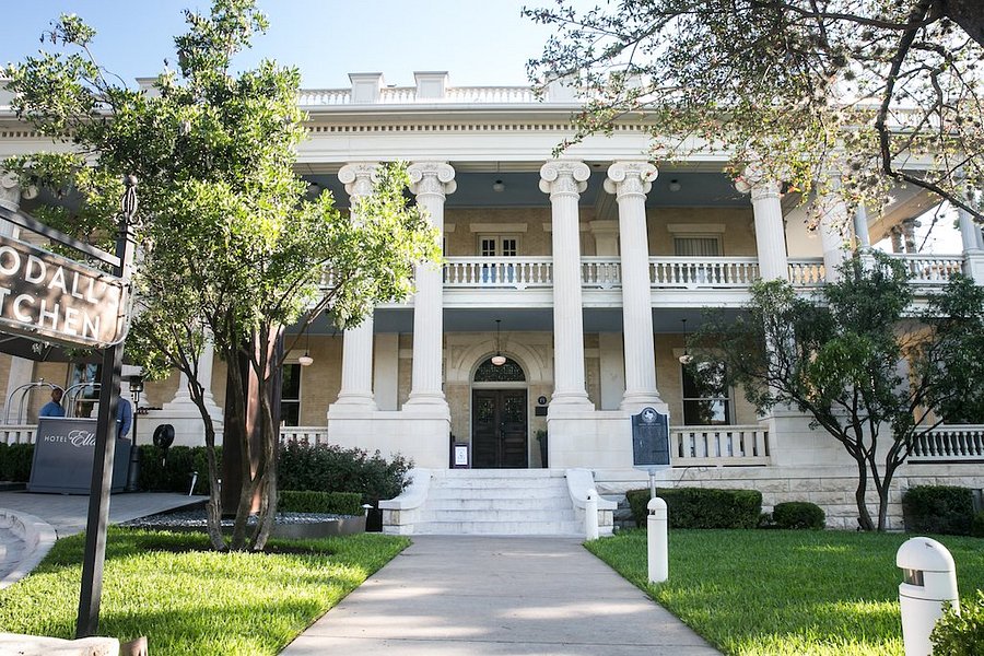 The historic white mansion at Hotel Ella in Austin, with a lawn and trees