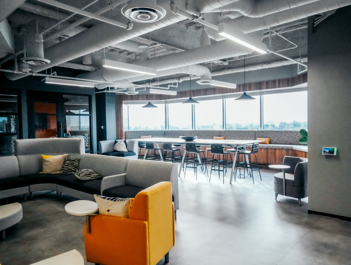 Rexford office lounge with shared tables, sofas and exposed ceiling services
