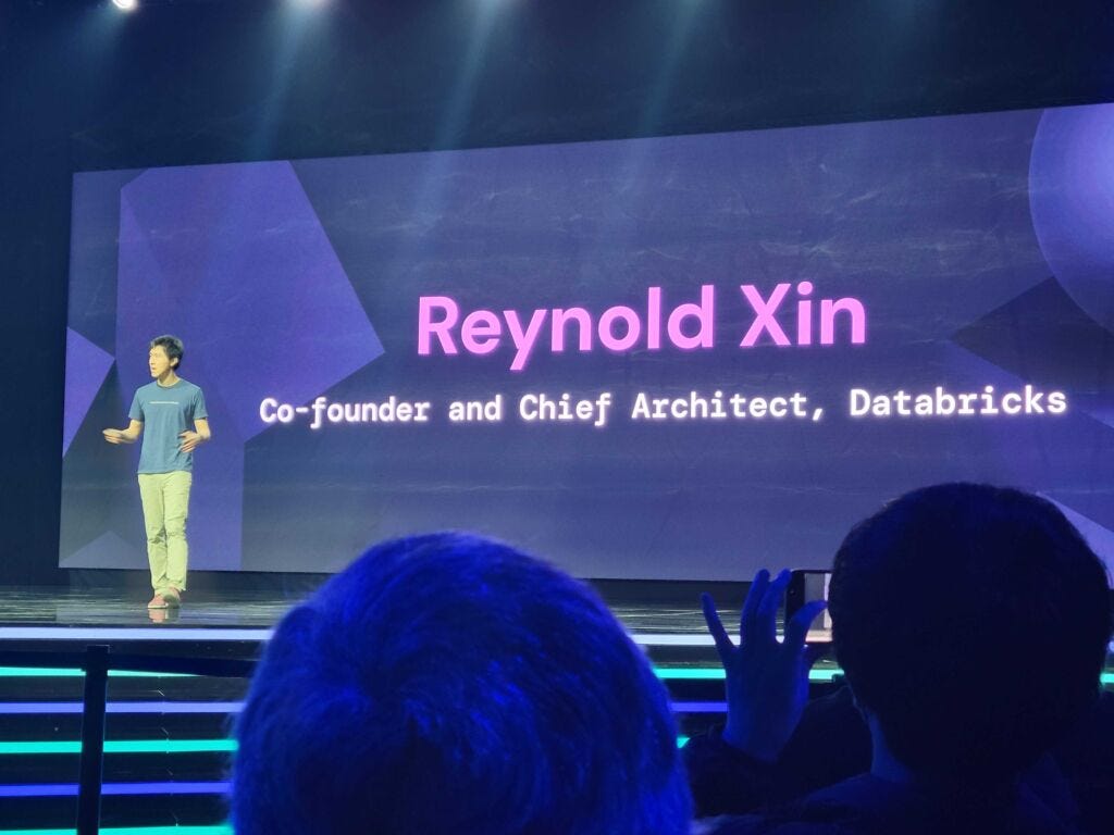 Reynold Xin presenting on a large conference stage at the 2023 Data and AI Summit
