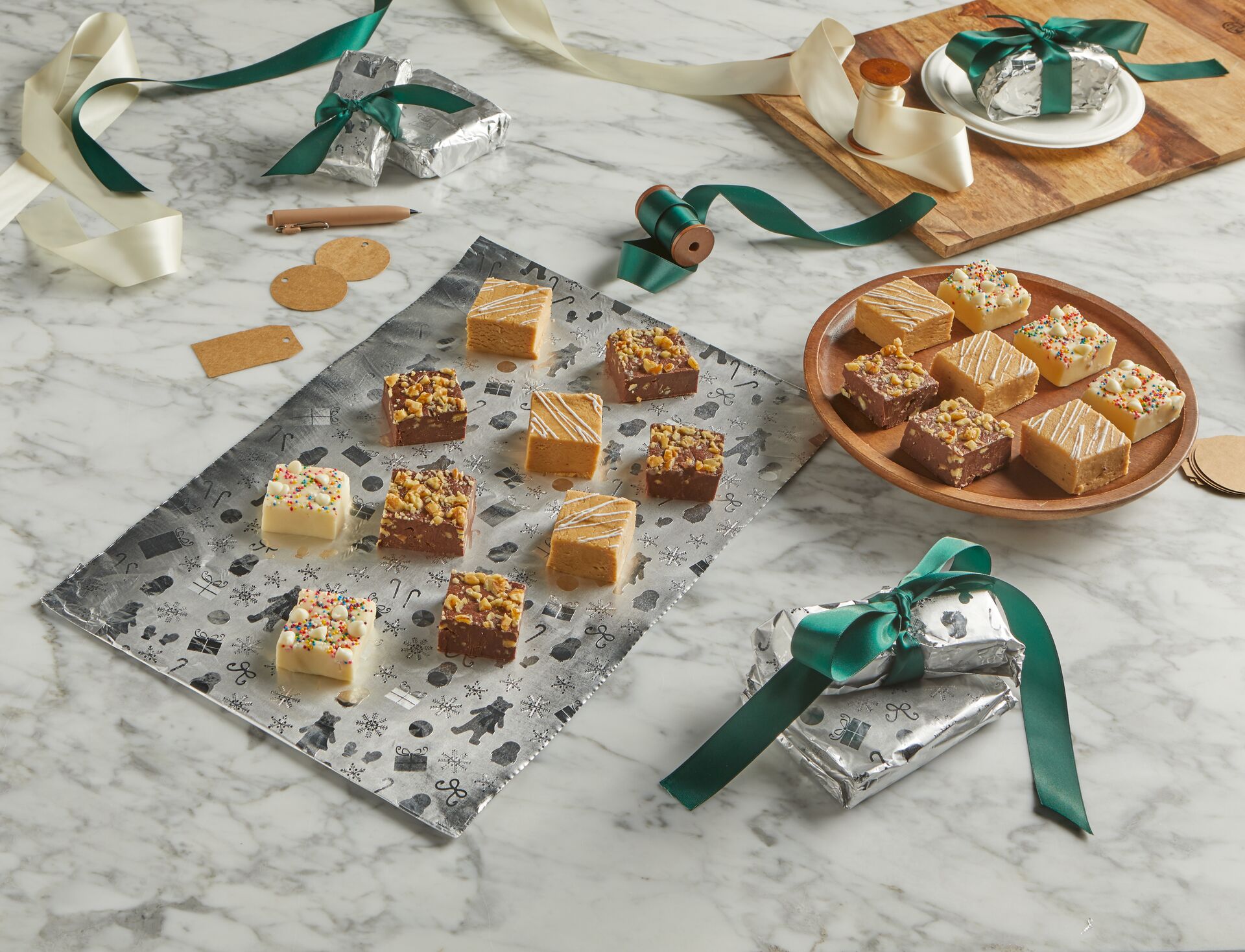 Homemade fudge on holiday-patterned foil with ribbon-tied foil packages nearby