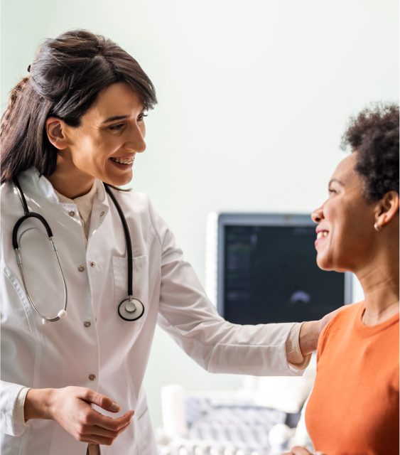 A physician speaking warmly with a patient in an exam room