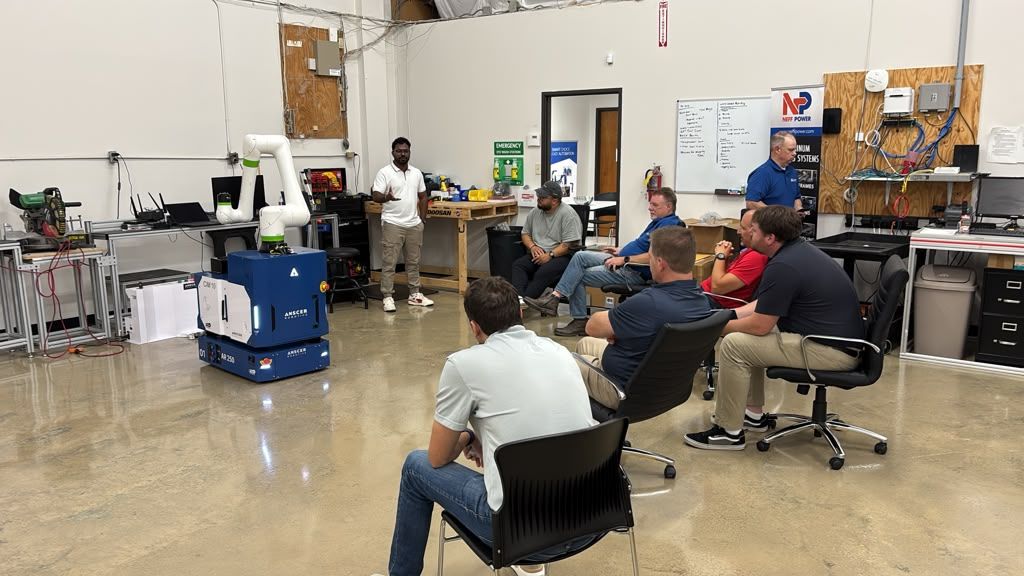 Partners seated around an ANSCER mobile robot and collaborative arm during practical training