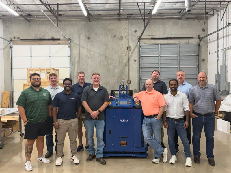 Ribin Mathew and ANSCER colleagues with US integration partners beside a blue robot