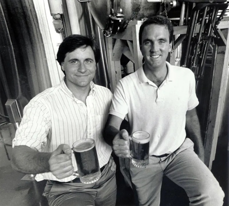 Rich Doyle, left, and Dan Kenary holding mugs inside the Harpoon brewery