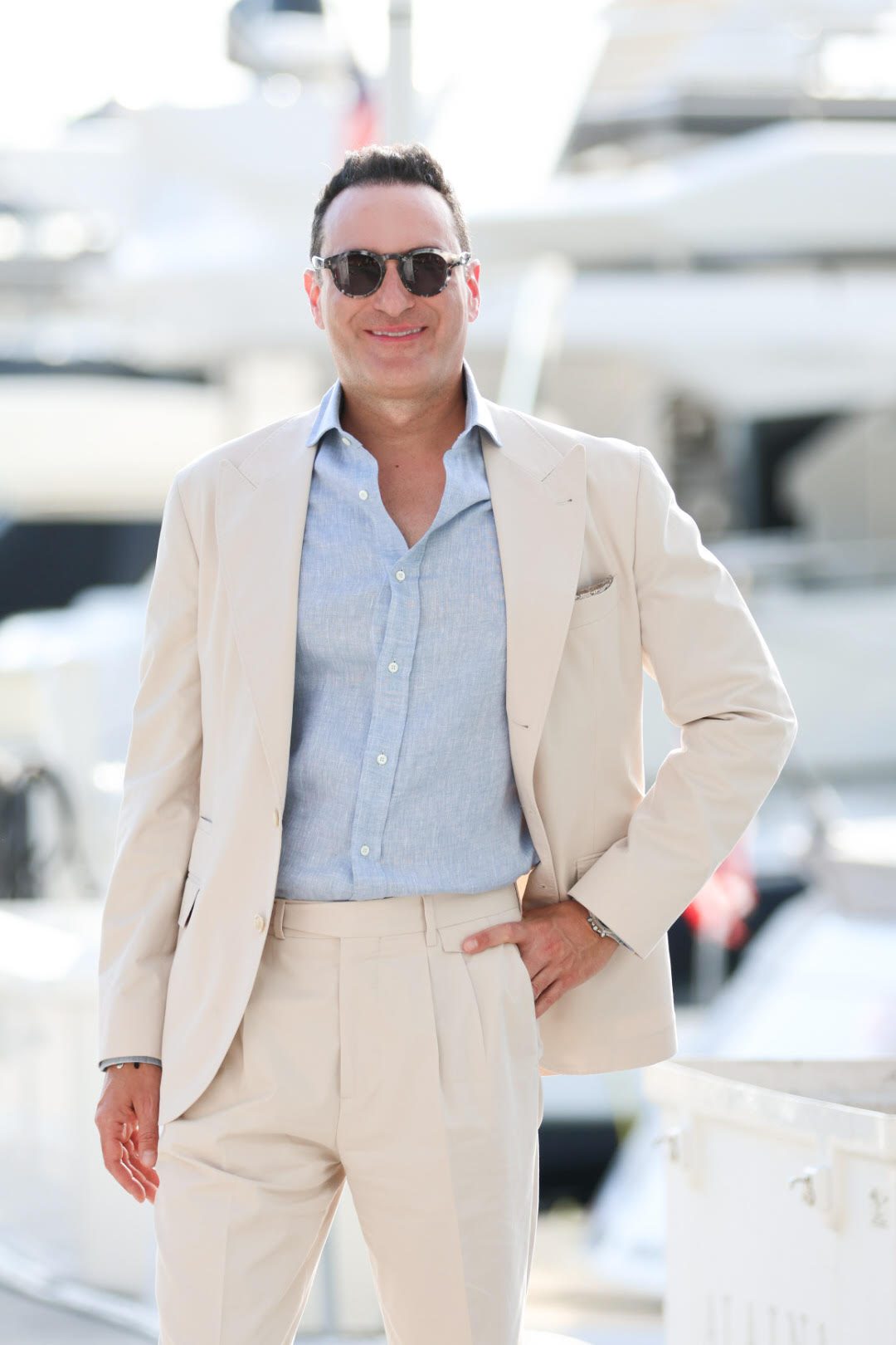 Richard Awdeh in a light suit and sunglasses beside a marina