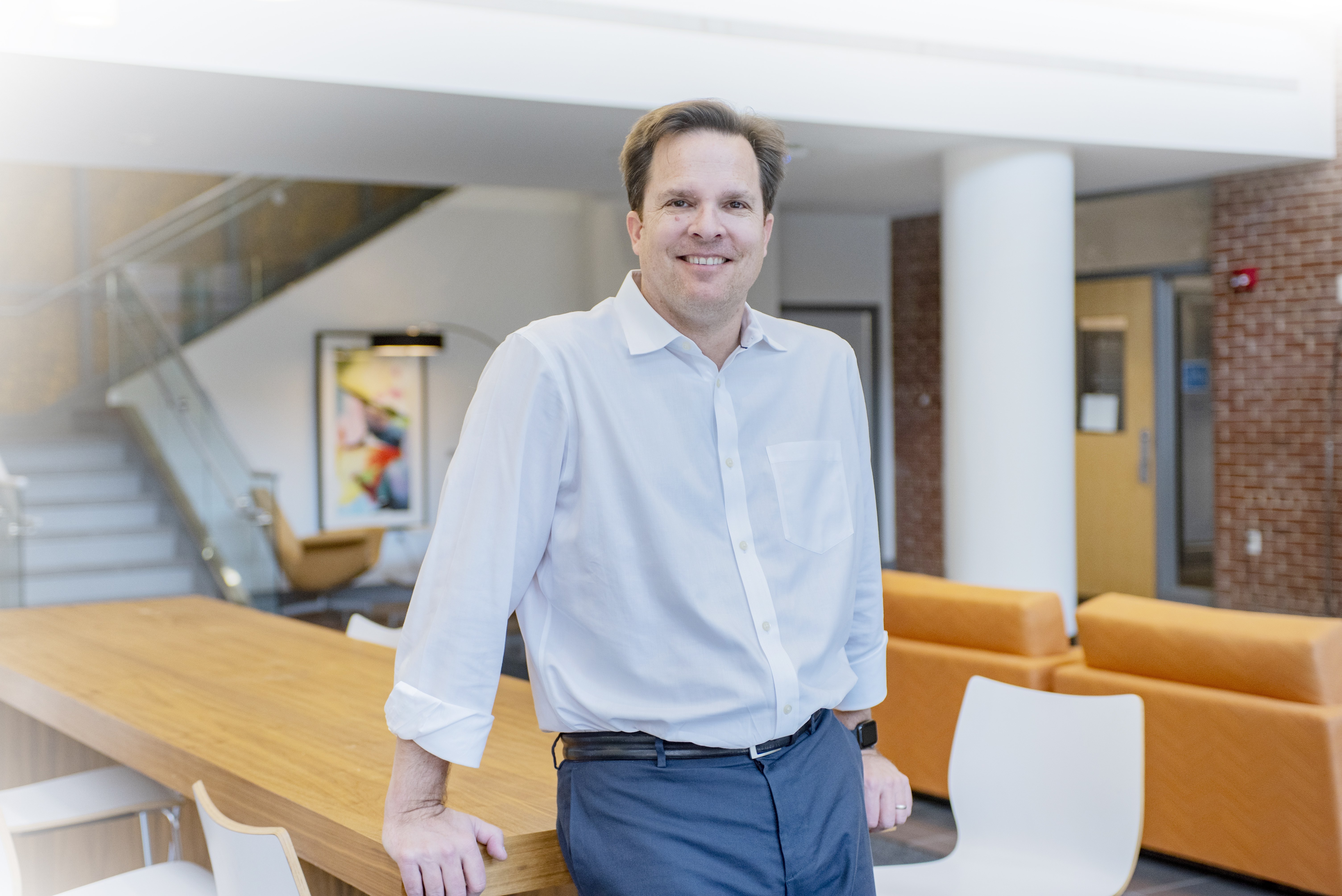 Richard Batycky standing beside a communal table in a bright workplace