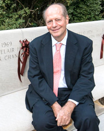 Richard Hayne seated outdoors in a suit and pink tie